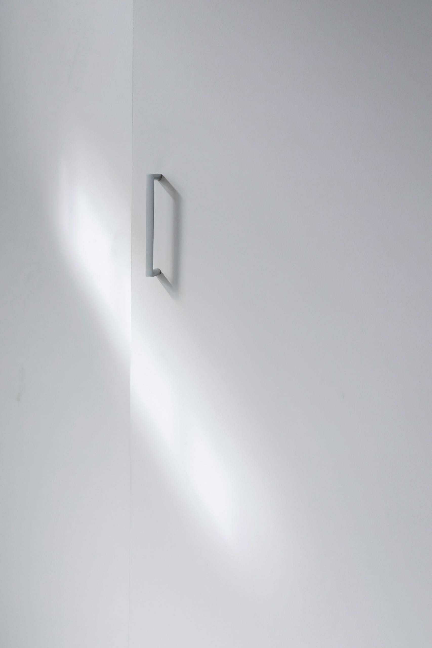 A minimalistic white cabinet door with a sleek handle, perfect for modern interior design.