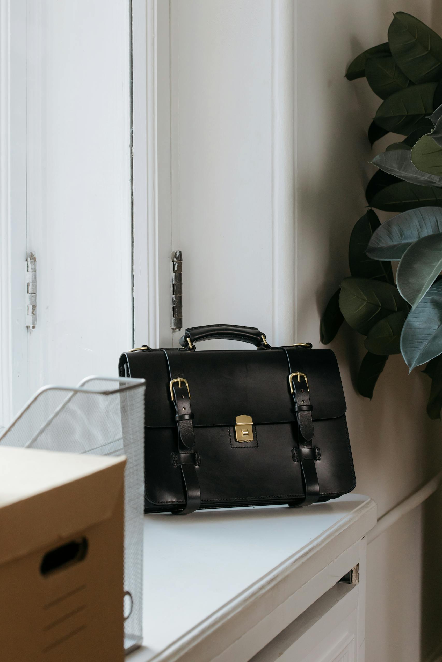 Stylish black leather briefcase on a desk in a minimalist office, perfect for business or professional use.